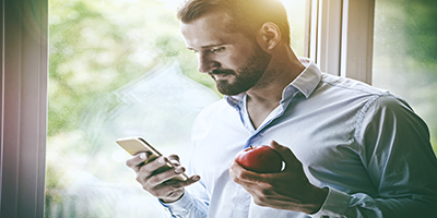 A man holding a phone and an apple.