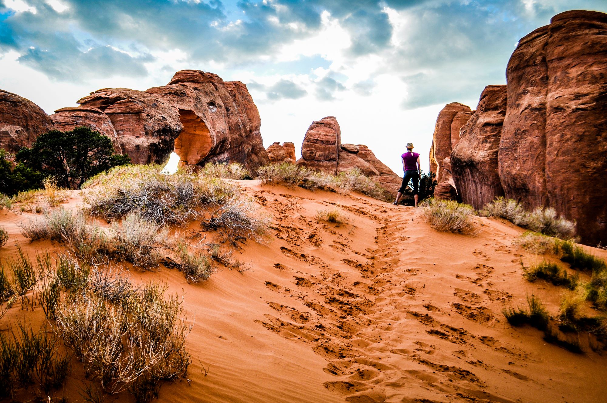 A female hiker on a sandy trail.